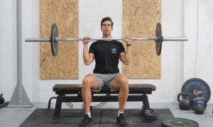 man seated overhead press barbell