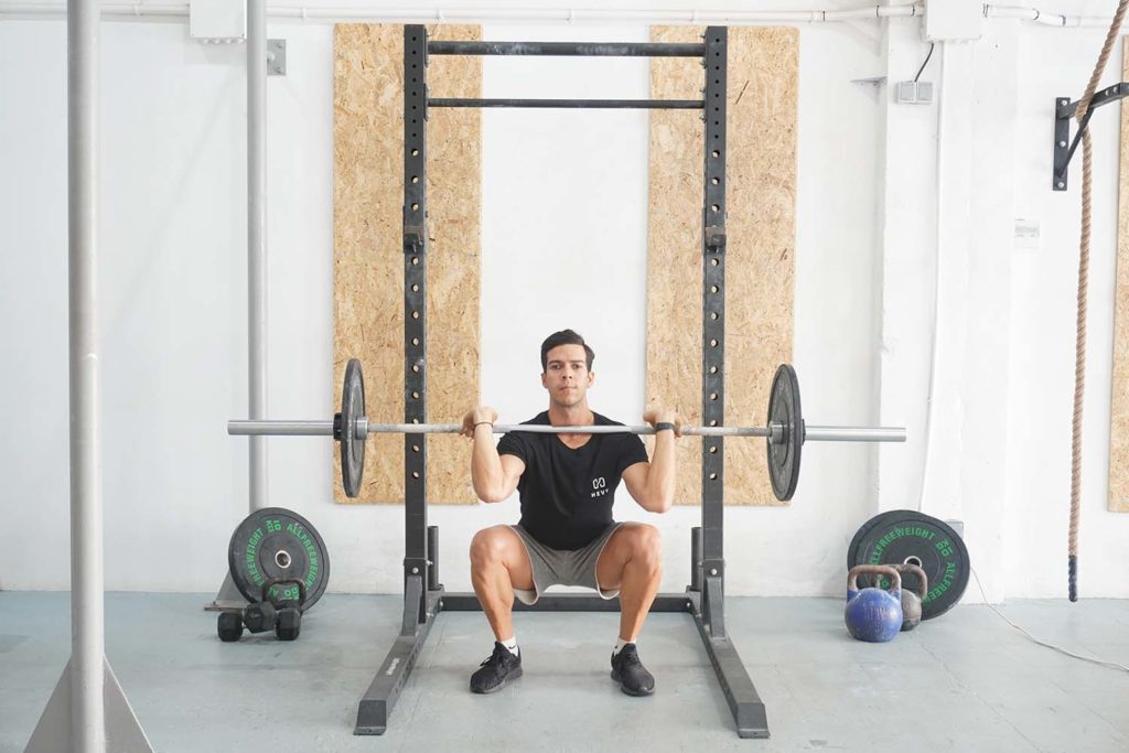 man full front squat barbell Compound vs. Isolation Exercises